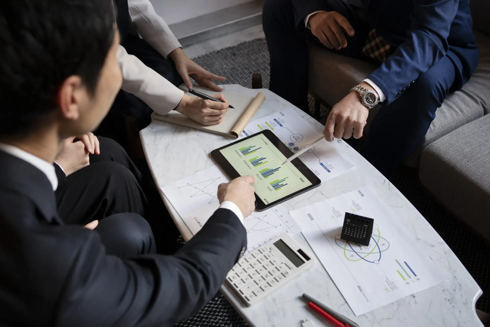 Advisor and clients reviewing financial charts on a tablet during a planning meeting