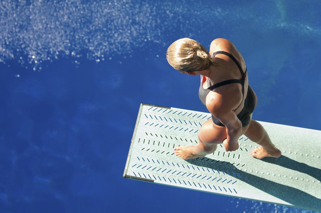 Professional lady diver preparing to dive from the spring board