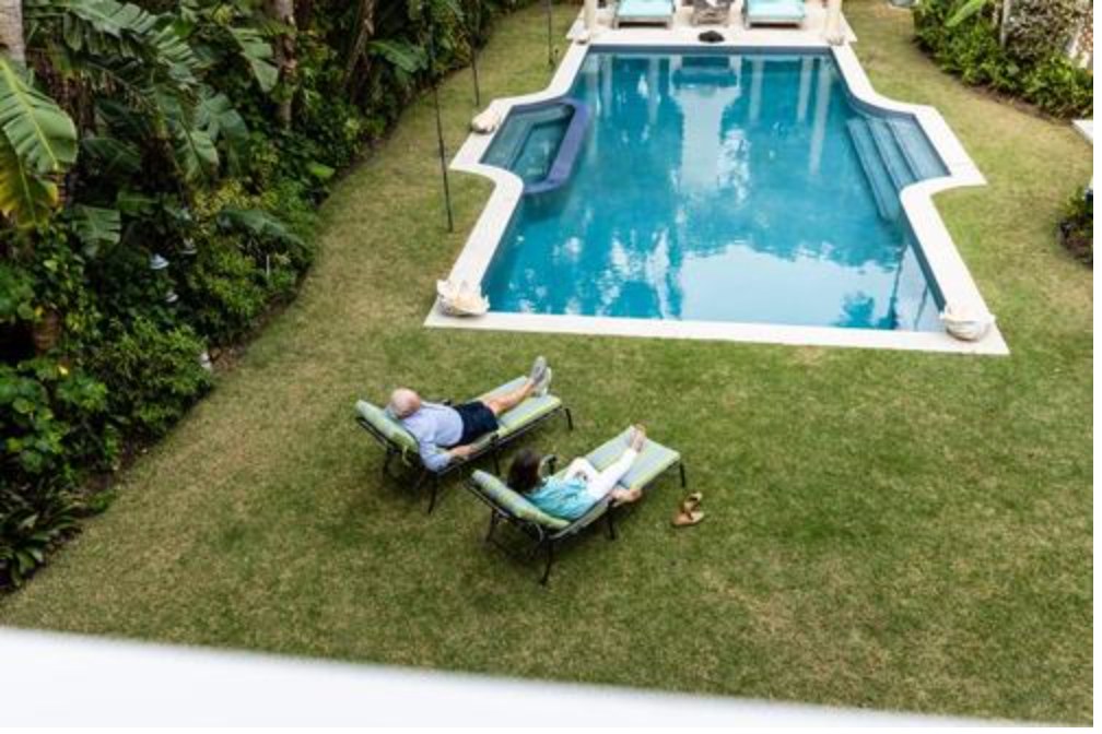 Retired couple relaxing on lounge chairs beside a backyard pool