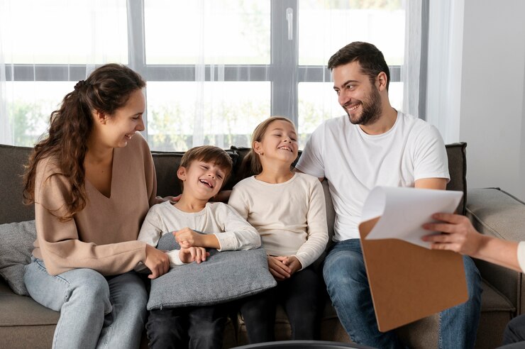 Smiling family of four on a sofa reviewing life insurance paperwork with an advisor