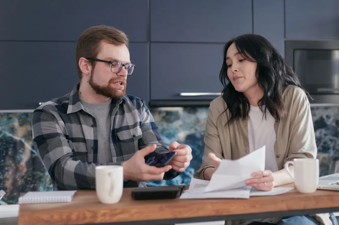 Couple reviewing household savings and bills at the kitchen table