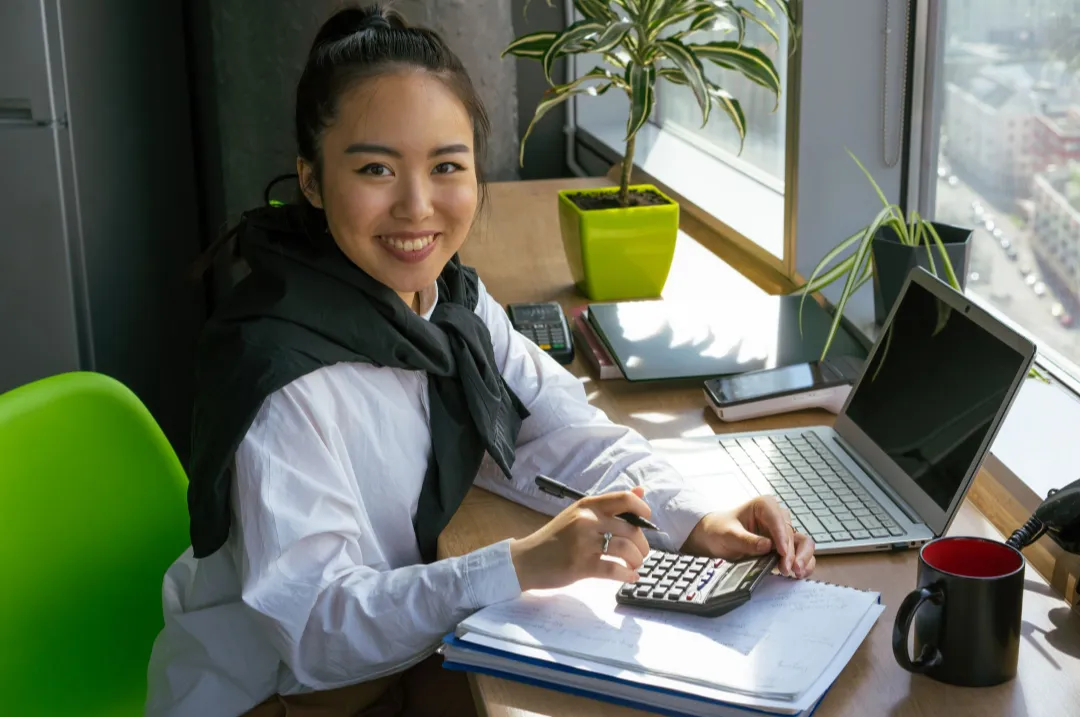 Young woman planning her personal budget with a calculator and notebook